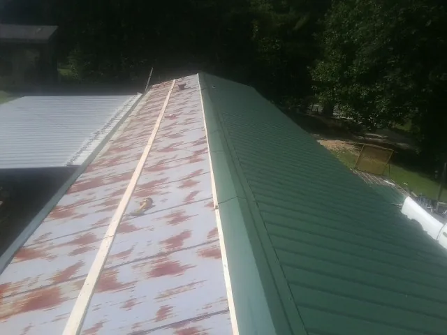 Old rusted panels beside newly installed green metal roofing — Wind Damage Roof Repair by Roofing Brothers in Pitman