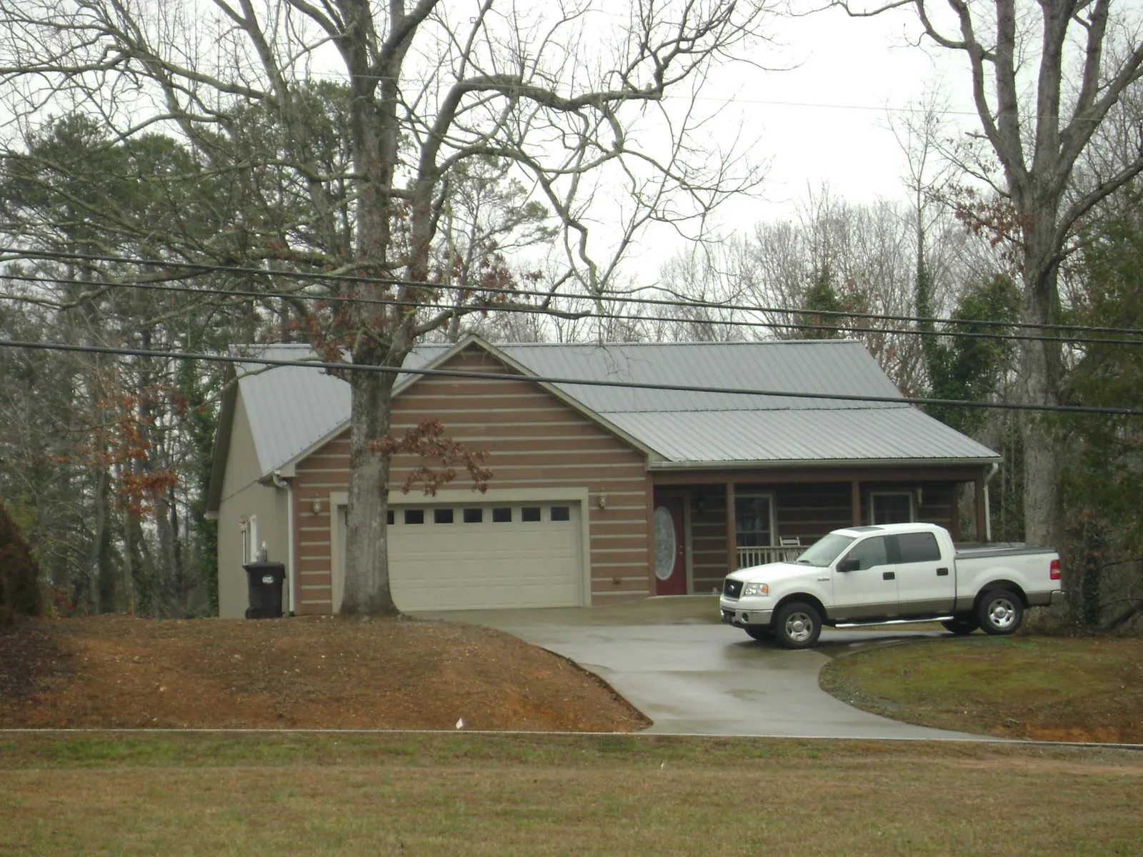 Gray metal roof on a log sided house with an attached two car garage in Pitman